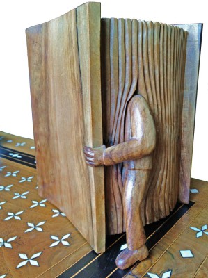 Sculpture en bois représentant un homme entrant dans un livre